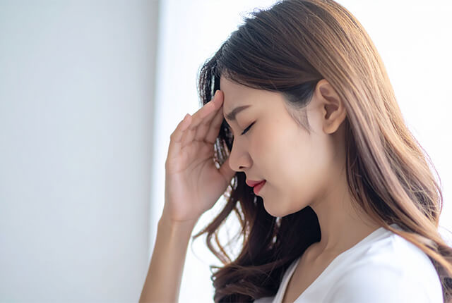 おでこに指先を当てている女性